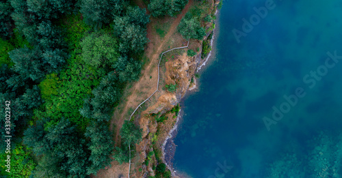 Aerial top view of a famous wild coastline with green flora, high cliff and turquoise blue waters. Epic wallpaper