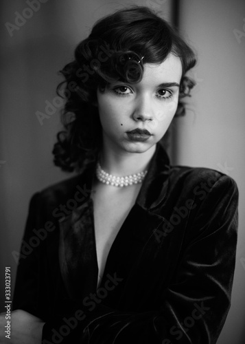 Portrait of a curly girl in the velvet jacket and perl necklace