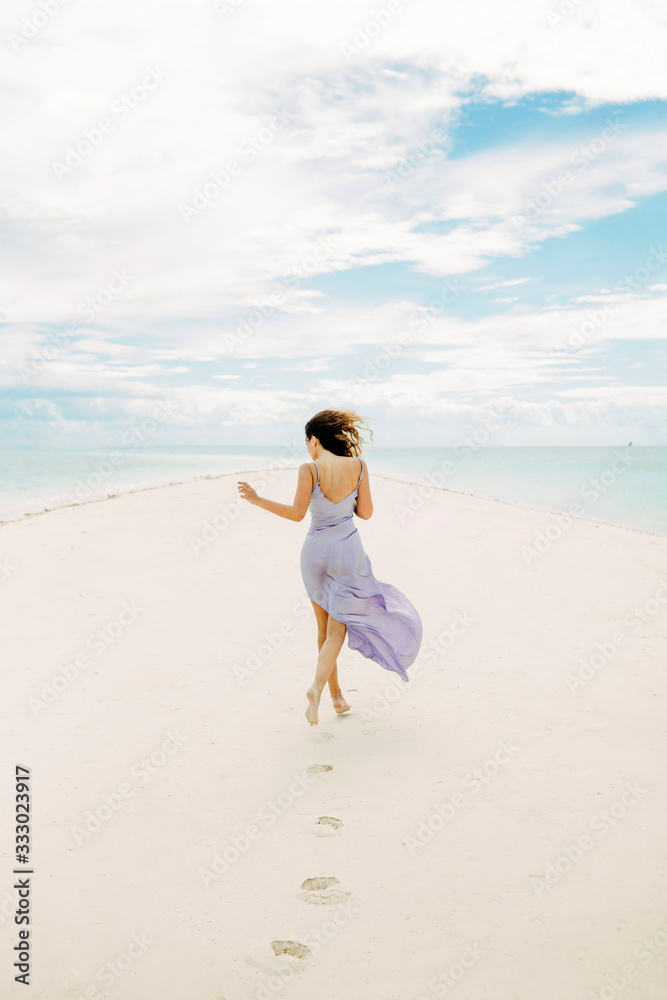 Woman in a dress walking in the empty beach Woman in a dress walking in the empty beach