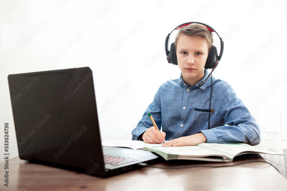 Distance learning in quarantine. A boy in headphones in front of a computer does his homework. Distance learning in quarantine. A boy in headphones in front of a computer does his homework.