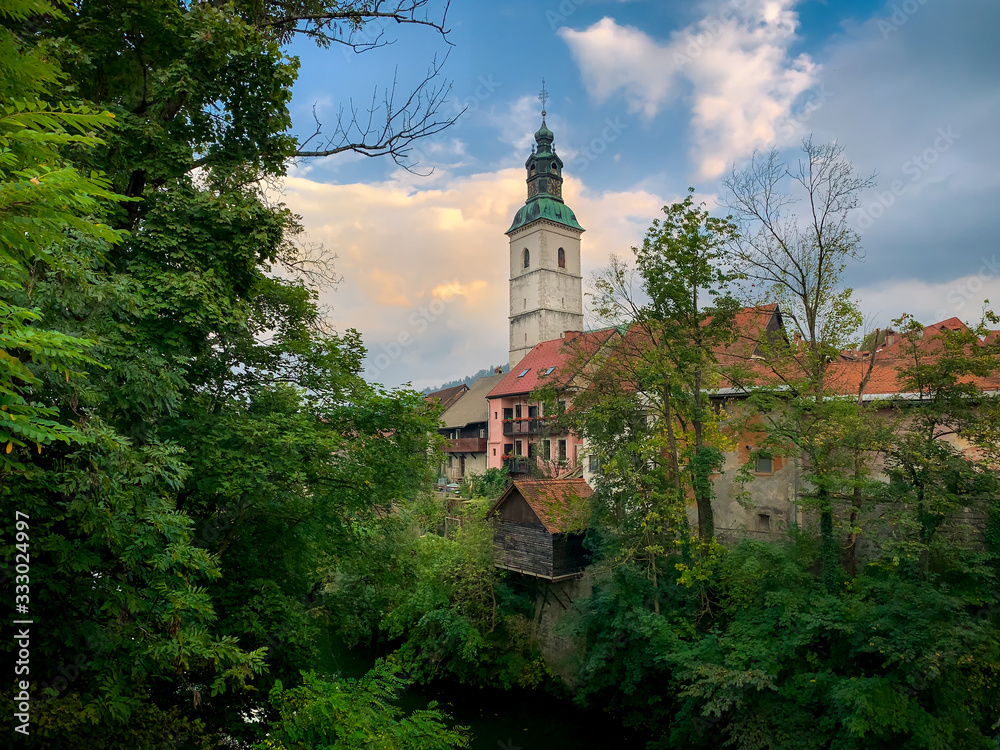 Scenic view of Skofja loka church and old houses with green foliage, Slovenia