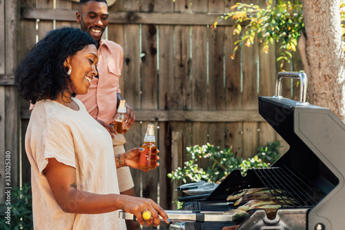 Woman Grilling Corn with Beer in Hand