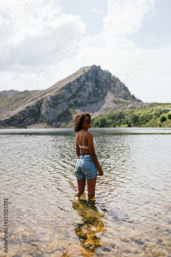 Happy brown skinned woman standing on a lake at Covadongas, in Europe Peaks in Asturias photo