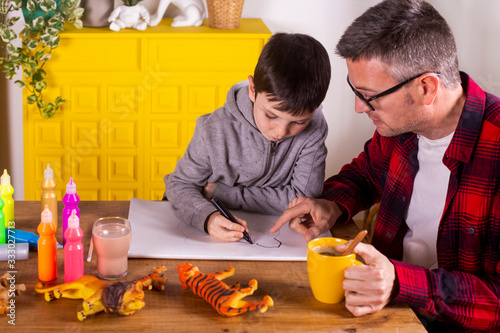 Father assisting his son in drawing while having a coffee. photo