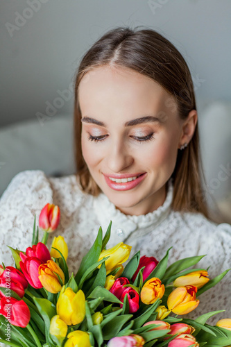 Beautiful young woman holds a multi-colored bouquet of tulips. Spring woman portrait. International Women's Day.