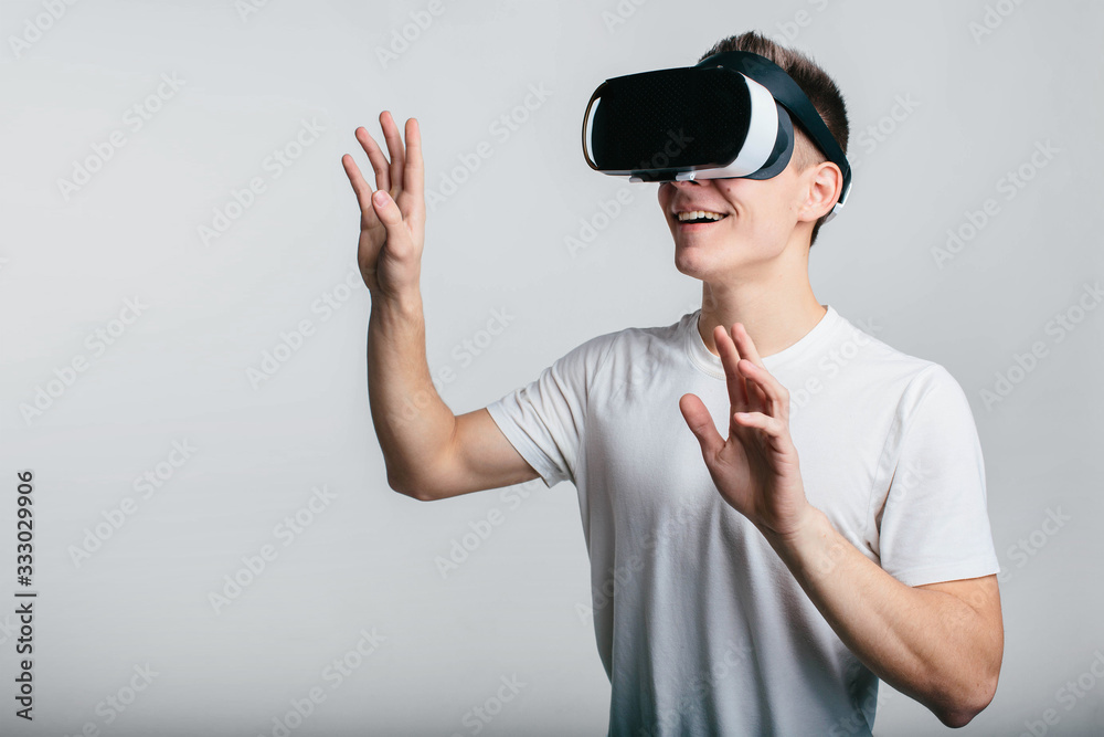 Man wearing virtual reality goggles. Studio shot, gray backgroun Man wearing virtual reality goggles. Studio shot, gray backgroun