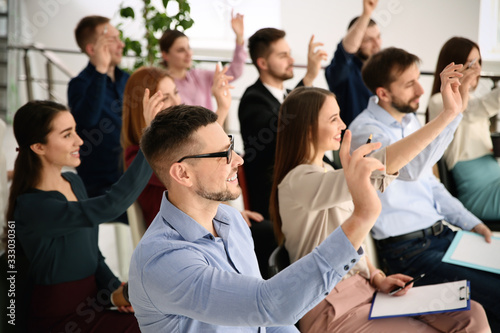 People raising hands to ask questions at business training indoors