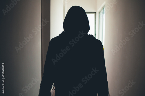 Silhouette of a man sneaking through the hallway of a house
