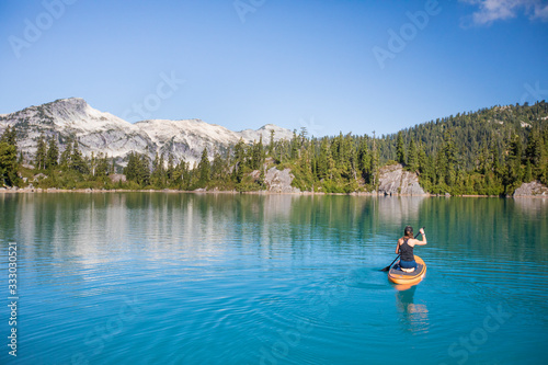 Attractive woman paddles Stand up paddle board on blue lake. photo