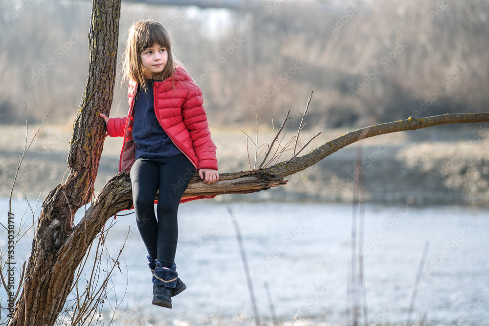 Φωτογραφία Portrait of a pretty child girl sitting on a tree branch in autumn outdoors