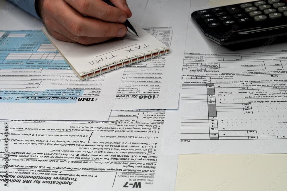 Obraz premium A person is completing the tax form with a pen.