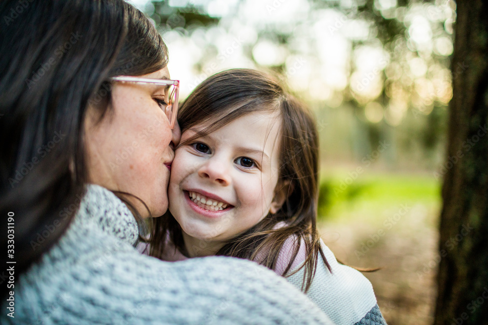Close up view of mother kissing and hugging young cute daughter. Close up view of mother kissing and hugging young cute daughter.