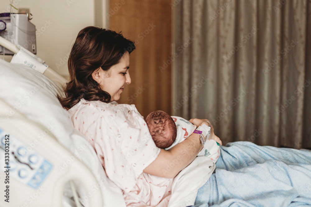 Side view of happy mother holding newborn son in hospital Side view of happy mother holding newborn son in hospital