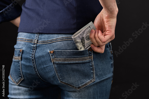 Girl removes money US dollars in the back pocket of jeans.