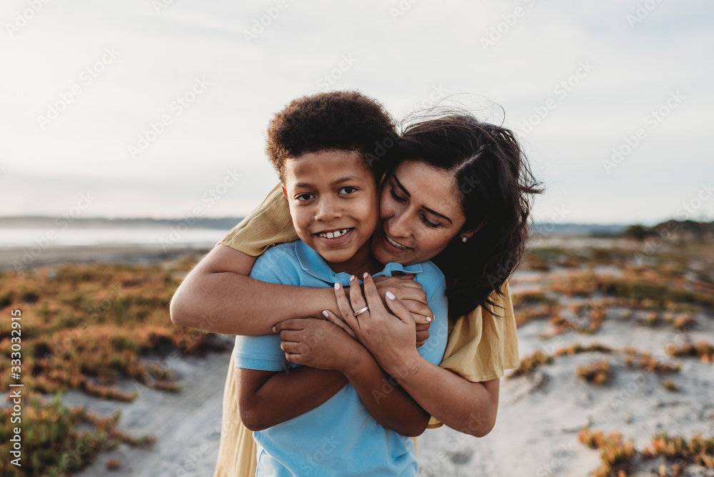 Front view close up portrait of young mother embracing son beach Front view close up portrait of young mother embracing son beach