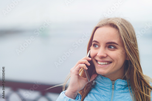 Emotional beautiful blonde talking on the phone outdoors. Female Corrupt faces and indulges in chatting with friends on the cell.