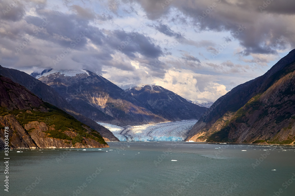 Beautiful view of Dawes Glacier with snow covered mountains while cruising in Endicott Arm near Juneau Alaska. Sunlight hitting the glacier. 