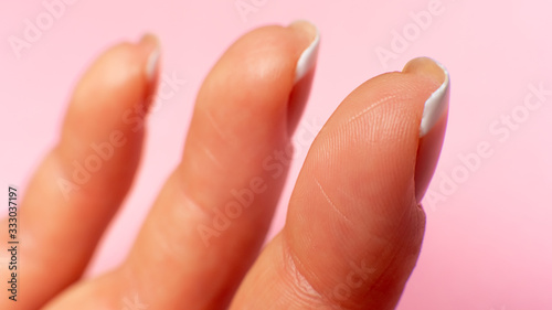 three fingers inside on a female hand, close-up. pink background.
