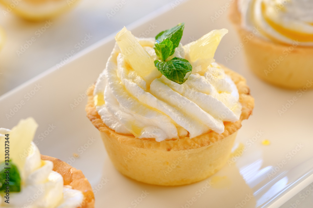 Tartlets with lemon kurd and italian meringue on a white plate Tartlets with lemon kurd and italian meringue on a white plate