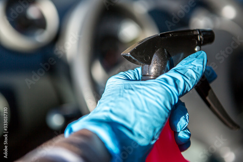 Coronavirus Epidemic Outbreak. Close-up of hand in protective glove using wet wipe to disinfect car interior. .  © Coolpicture