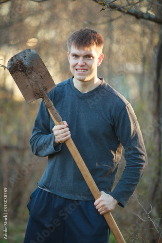 Agronomist handsome strong man with shovel on background of flower beds