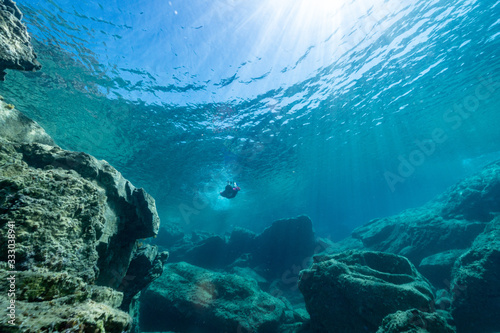 Woman freediver glides with fins. over rocky bottom sea. Freediving and beautiful light in blue sea.	Spectacularly clear waters.Woman freediver glides with fins. over rocky bottom sea. Freediving and 