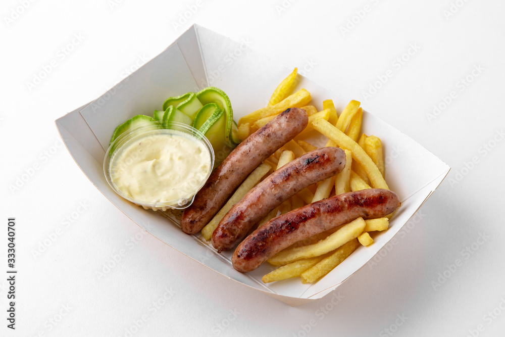 Lunch or dinner, sausages made from minced poultry, pork or veal with french fries and vegetables in paper packaging for take away or food delivery isolated on a white background. Lunch or dinner, sausages made from minced poultry, pork or veal with french fries and vegetables in paper packaging for take away or food delivery isolated on a white background.