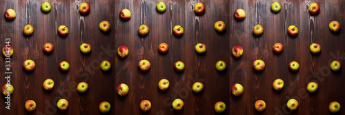 Fresh apples arranged systemically on a wooden background. Panorama as a background of apples.