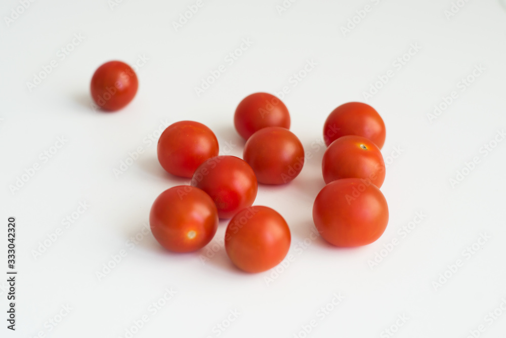 A handful of fresh ripe cherry tomatoes close-up on white background top view. A delicious and healthy ingredient for sauces, ketchup, pizza, and vegetarians A handful of fresh ripe cherry tomatoes close-up on white background top view. A delicious and healthy ingredient for sauces, ketchup, pizza, and vegetarians