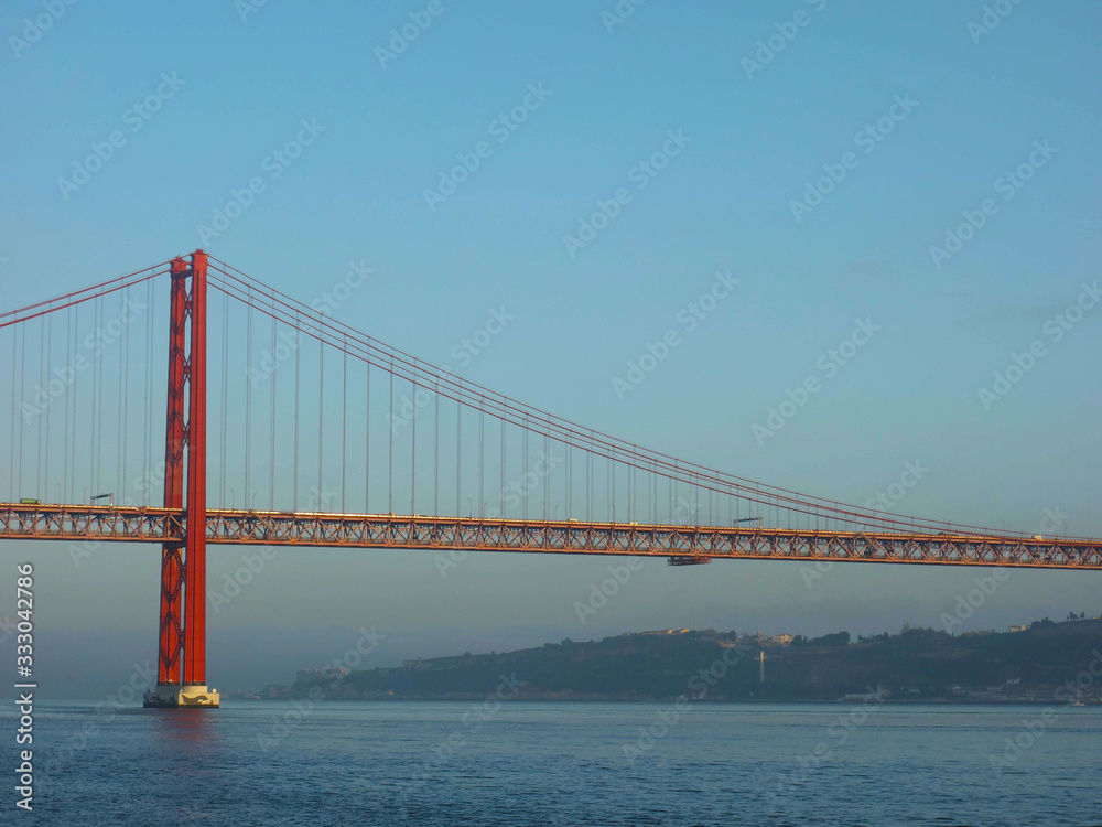 Lisbon, Portugal-23 December 219: skyline, red bridge on 25 April crossing the river Tejo on a cloudy day at dusk.