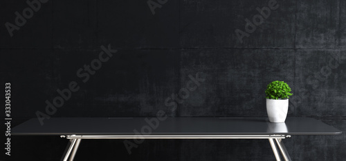 Work space stand mock up with table and plant front black concrete wall