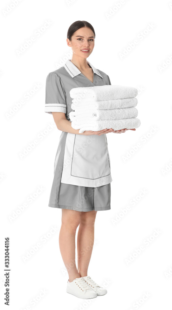 Young chambermaid holding stack of fresh towels on white background