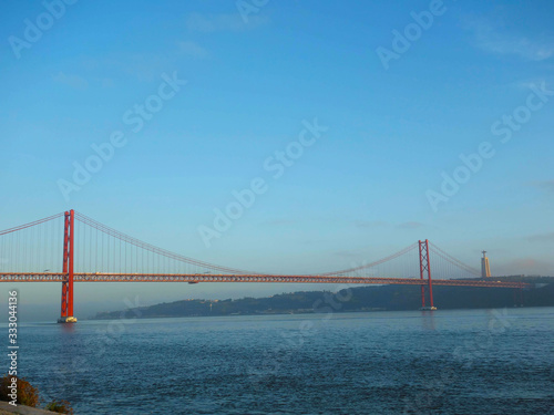 Lisbon, Portugal-23 December 219: skyline, red bridge on 25 April crossing the river Tejo on a cloudy day at dusk in the background Christ the King.