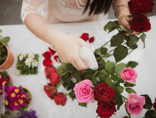 Woman Preparing to trim red and pink roses and beautiful flower arrangements in the home, flower arrangements with vase for gift-giving for Valentine's Day and Business in the family on the on table