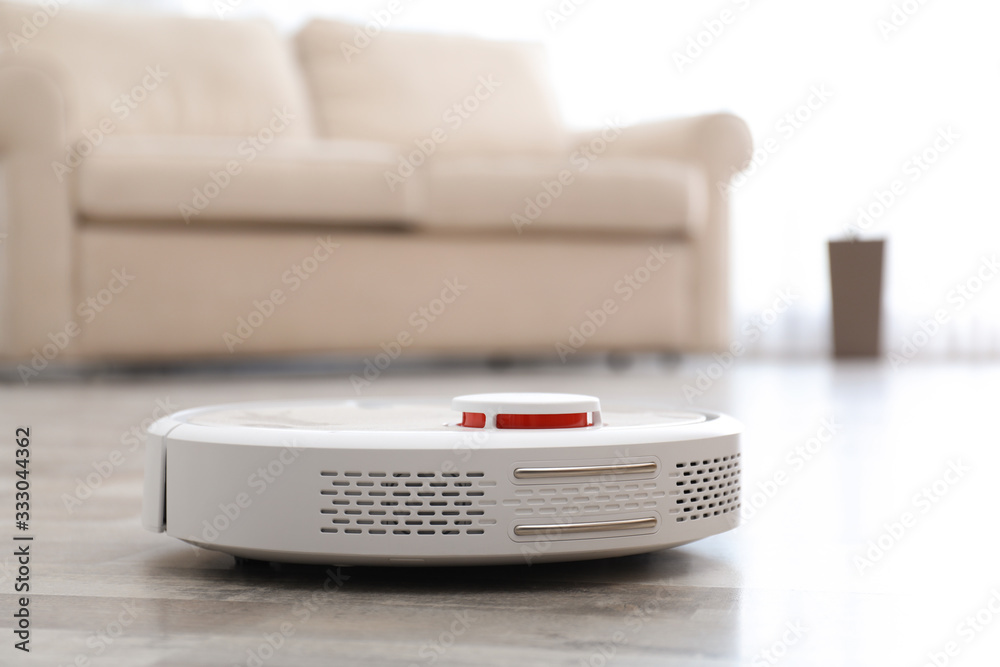 Modern robotic vacuum cleaner on floor in living room. Space for text Modern robotic vacuum cleaner on floor in living room. Space for text