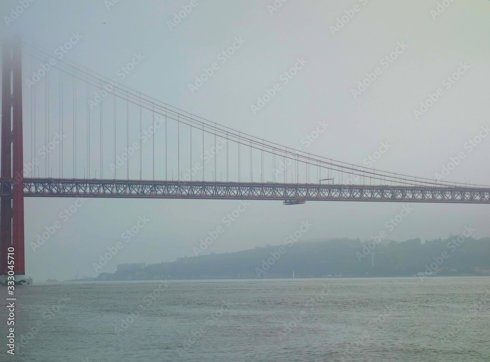Lisbon, Portugal-23 December 2019. Bridge on 25 April 2019 crossing the river Tejo on a foggy day. Lisbon, Portugal-23 December 2019. Bridge on 25 April 2019 crossing the river Tejo on a foggy day.