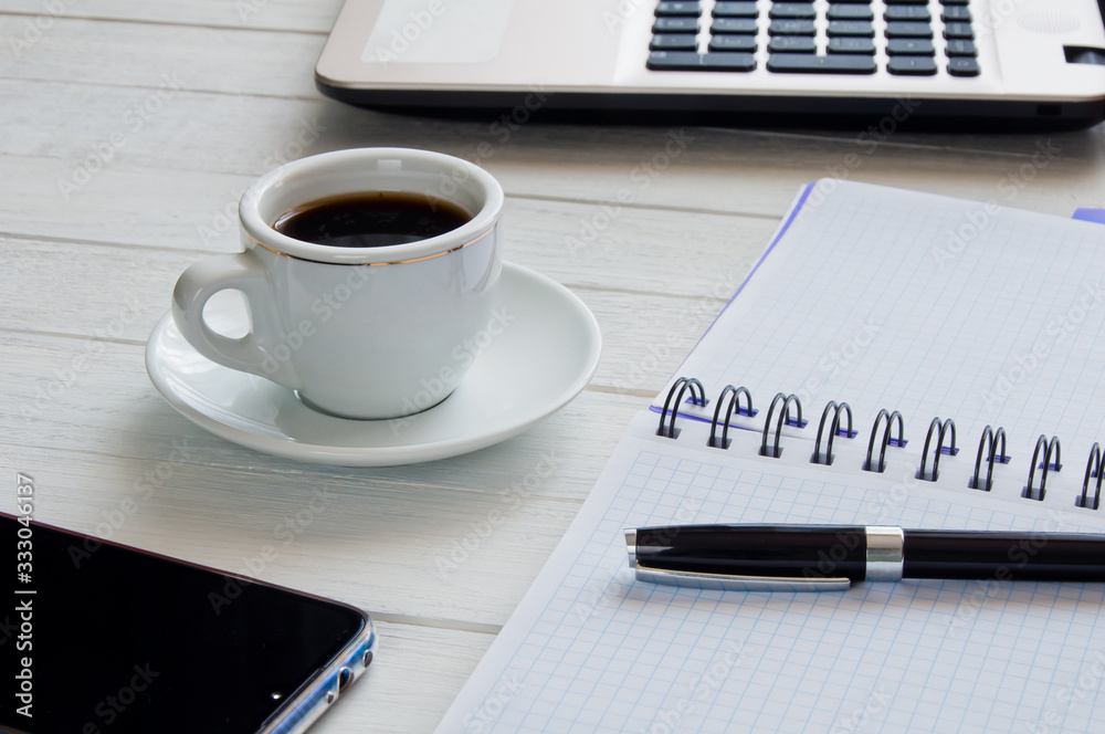 Cup of coffee, notebook with pen and laptop on white desktop Cup of coffee, notebook with pen and laptop on white desktop