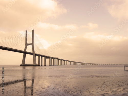 Bridge Vasco de Gama Lisbon crossing the river Tejo reflected in the water on a cloudy day. © Ombres