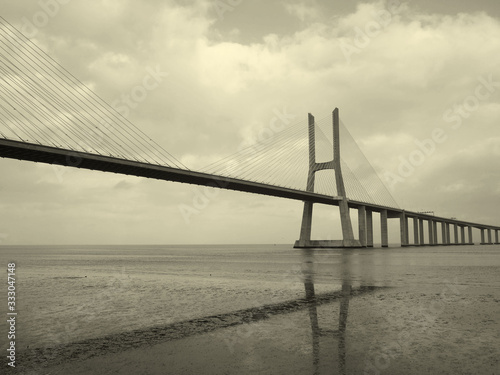 Bridge Vasco de Gama Lisbon crossing the river Tejo reflected in the water on a cloudy day.