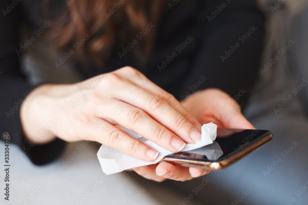 Hand wiping down smartphone surface due to corona virus crisis