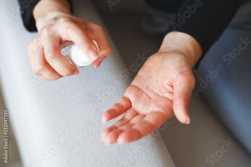 woman disinfecting hands with hand disinfectant spray in a bottle due to corona virus infection risk