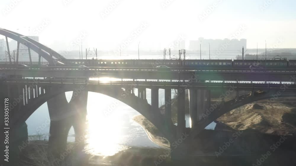Darnitsky bridge over the Dnieper River. Ukraine city Kiev. Video from the drone. Accompaniment by a drone passing a city electric train at dawn Darnitsky bridge over the Dnieper River. Ukraine city Kiev. Video from the drone. Accompaniment by a drone passing a city electric train at dawn