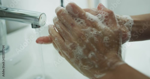 Handwashing - Washing hands woman rubbing soap with running water at sink, Coronavirus prevention hand hygiene. Corona Virus pandemic protection by cleaning hands frequently thoroughly. SLOW MOTION.
