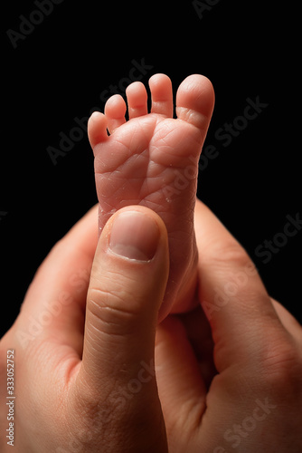 The foot of a newborn baby in the hands of his father. Baby foot and male fingers © Nataliya Schmidt