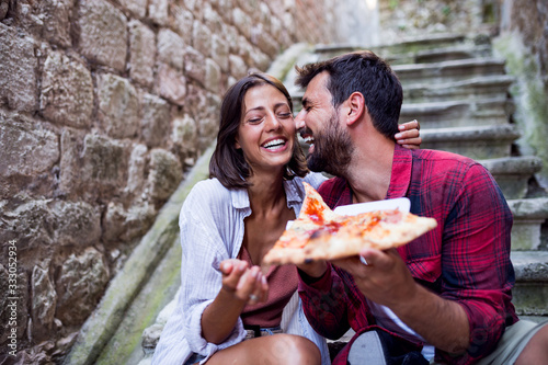 Smiling love couple eating pizza at street