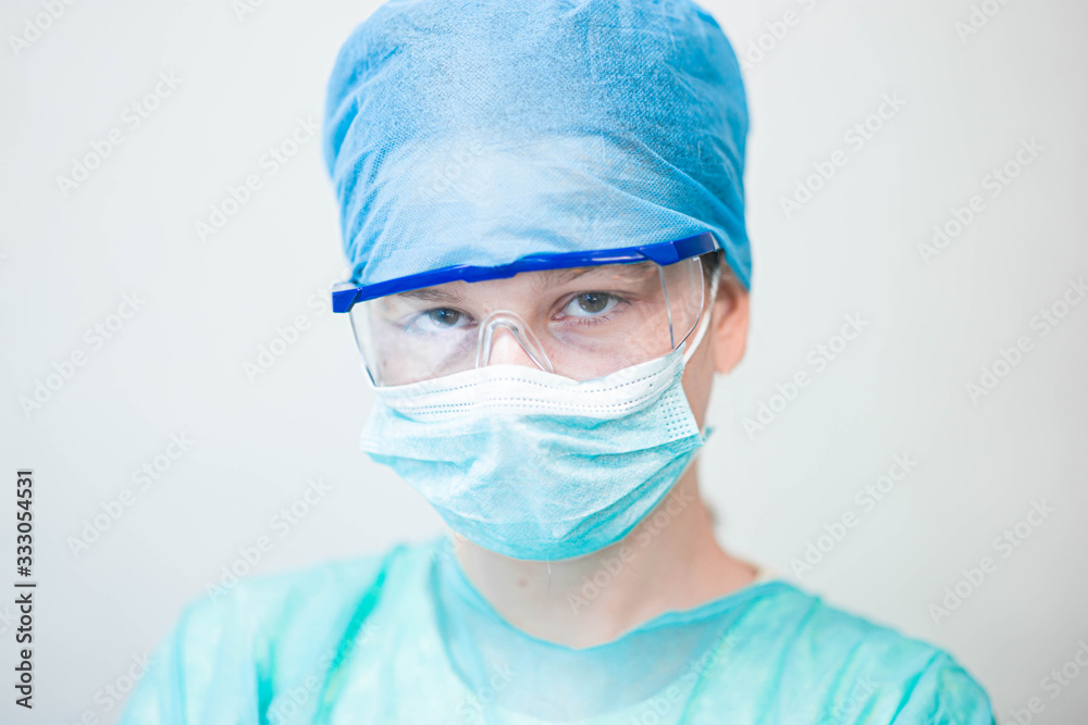 Female doctor in uniform, glasses and mask works concentrated in the hospital. portrait of a surgeon. Female doctor in uniform, glasses and mask works concentrated in the hospital. portrait of a surgeon.