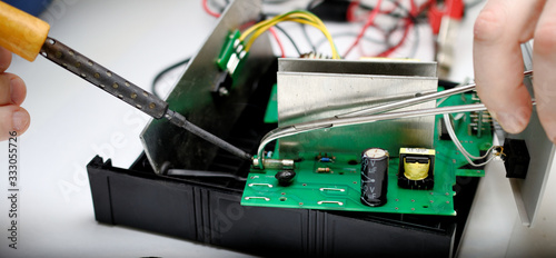 Canvas Print An engineer repairs a faulty power supply. solder fuse.