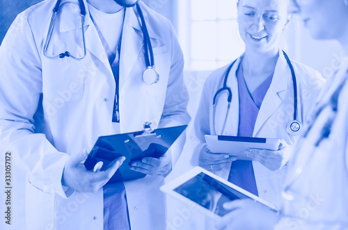 Doctors using a tablet in hospital standing in office