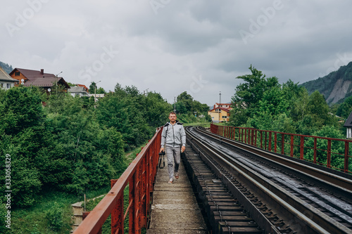 Handsome man with camera on forest background. Man on railroad track