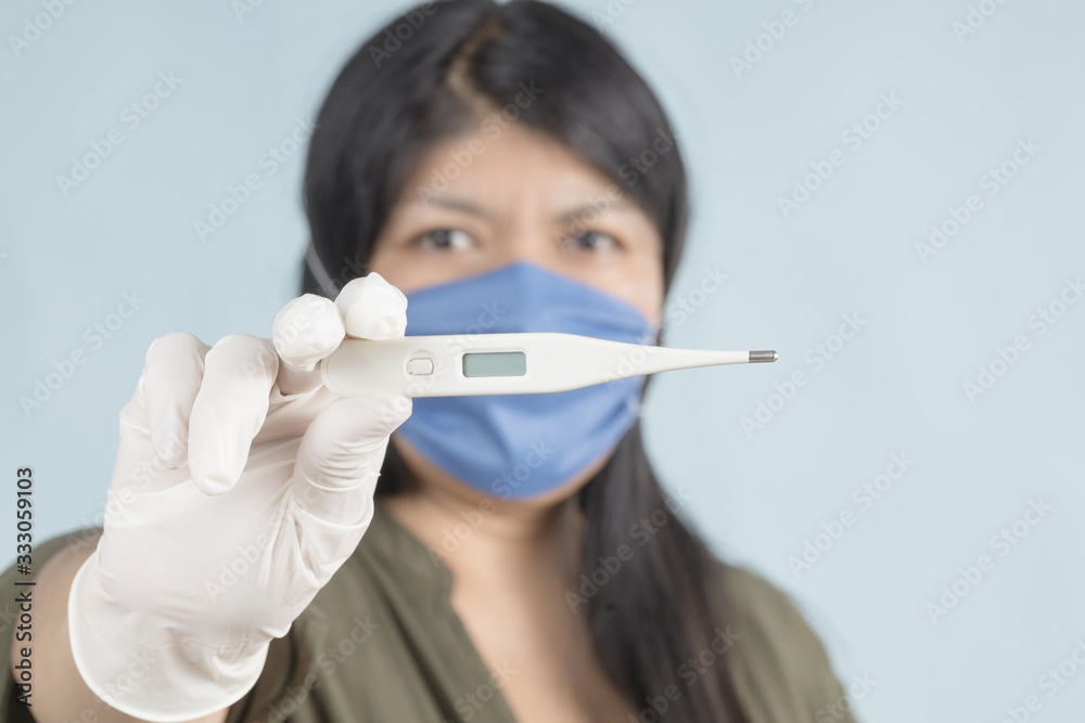 .woman with face mask showing thermometer .woman with face mask showing thermometer